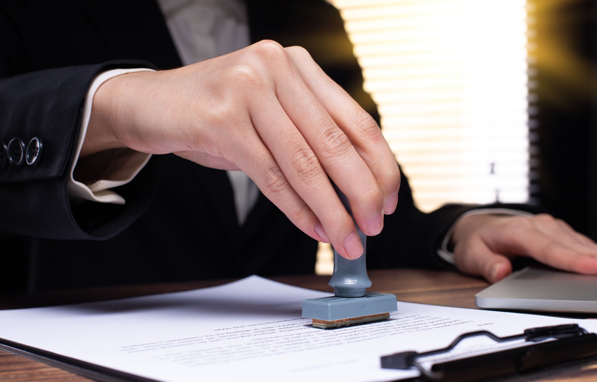 Person Signing Approval document, certificate, legal agreement in office by pen and stamp hand. Authority apply law to do contract paperwork form by public notary clerk or official lawyer, copy space